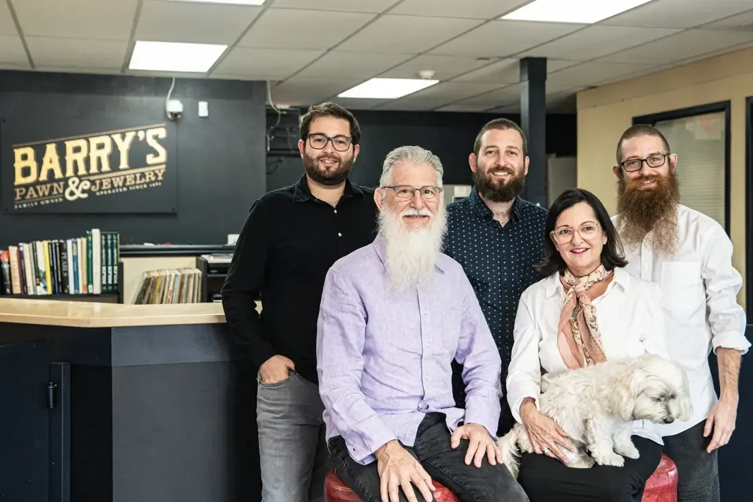 Three generations of the family behind Barry's Pawn & Jewelry, gathered at the counter in the Boca Raton store with the family dog
