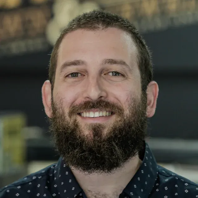 Evan, watch specialist at Barry's Pawn & Jewelry, in front of the Barry's sign in the Boca Raton store