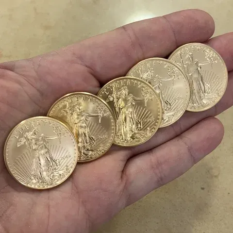 Five American Gold Eagle coins in a hand at the Barry's counter