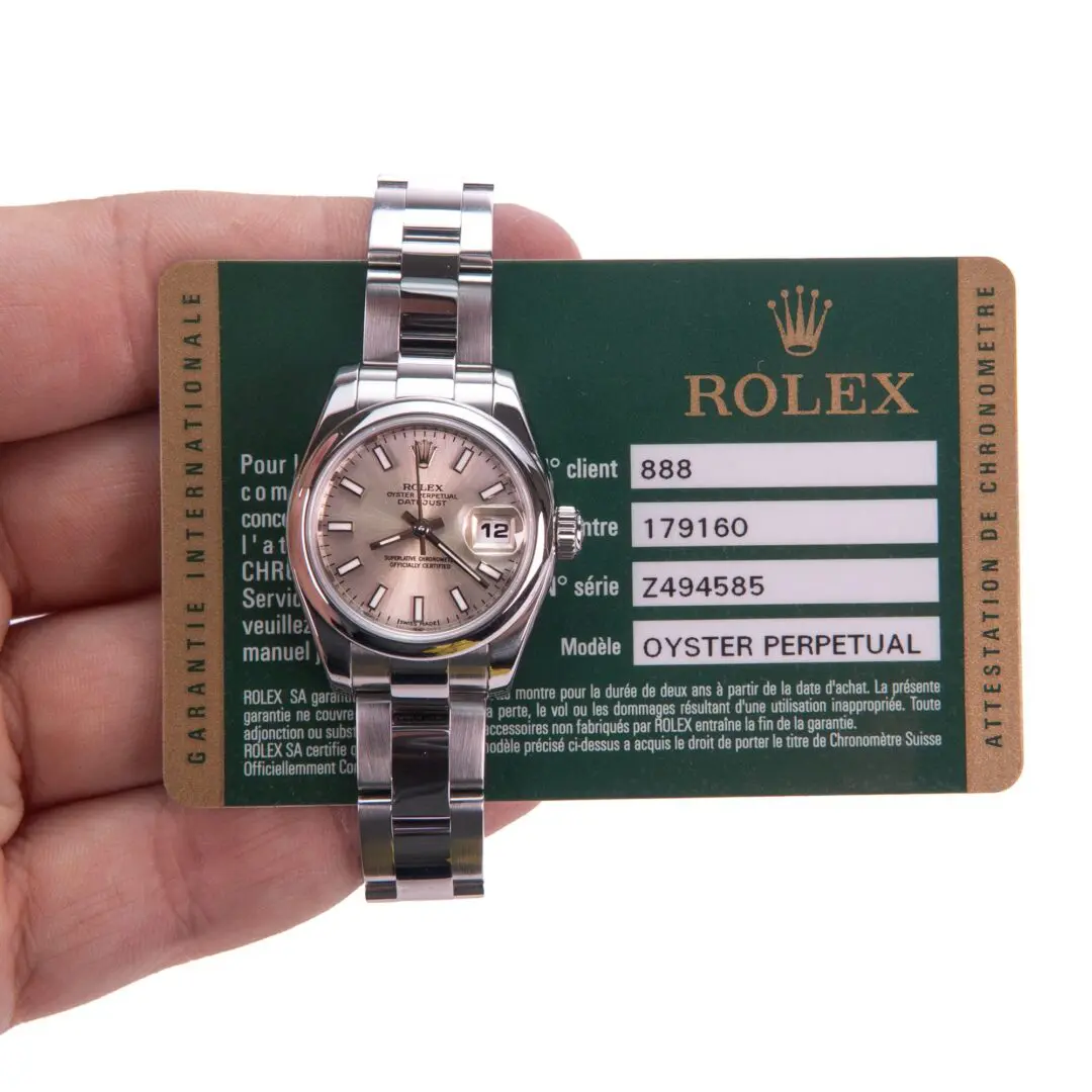 Hand holding Rolex watch and warranty card.