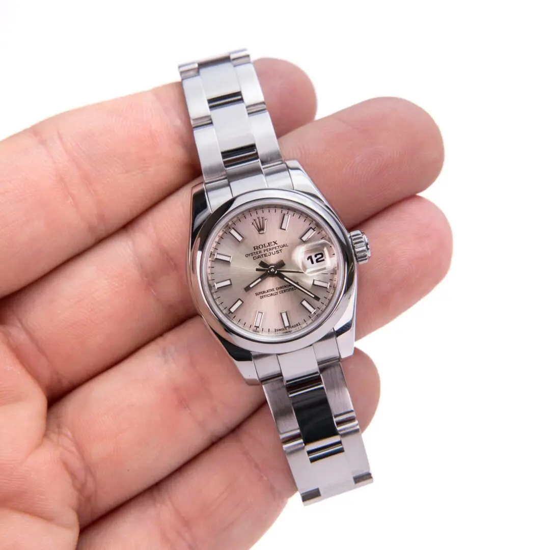 Hand holding a silver wristwatch close-up.