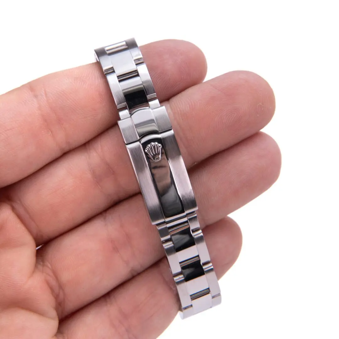 Hand holding a metal watch bracelet clasp.
