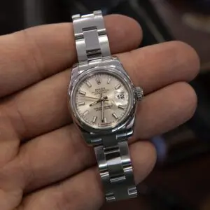 Silver wristwatch held in a hand.