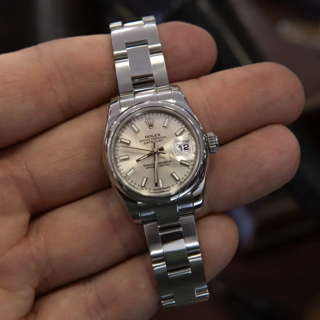 Silver wristwatch held in a hand.