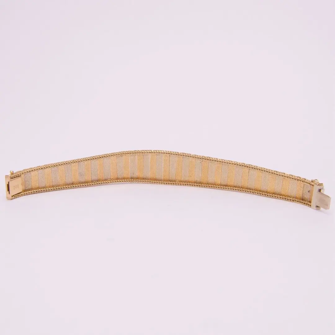 Gold mesh bracelet on white background.