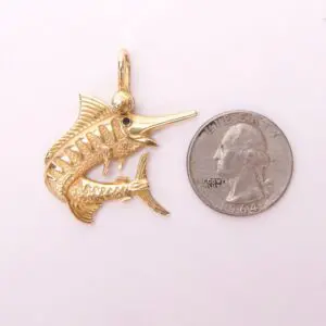 Gold fish pendant beside a quarter coin.