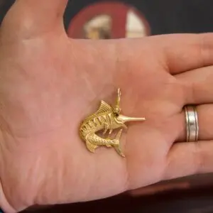 Hand holding a gold fish pendant.