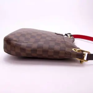 Brown checkered handbag with red strap.