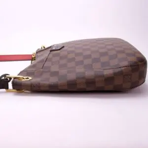 Brown checkered handbag with red strap.