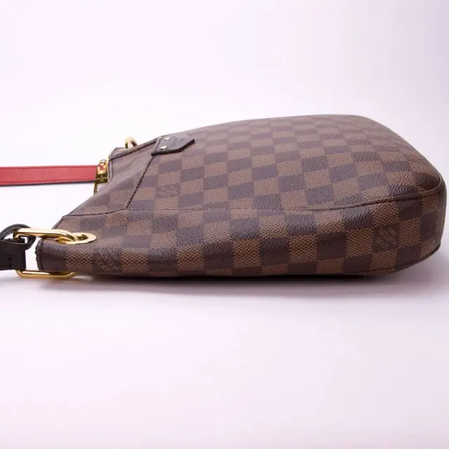 Brown checkered handbag with red strap.