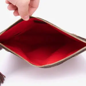 Open red-lined empty purse being held.