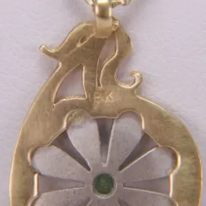 Gold pendant with floral design and gem.