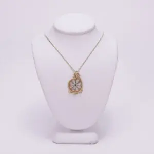 Gold pendant necklace on white display stand.