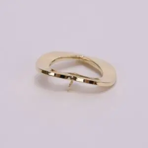 Gold abstract-shaped brooch on pink background.