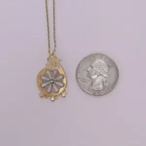 Necklace pendant beside a US quarter coin.