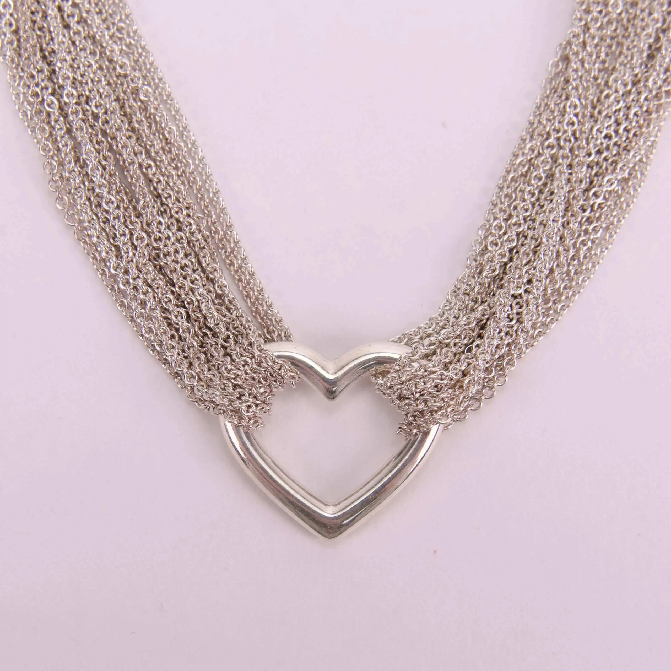 Heart-shaped silver necklace with multiple chains.