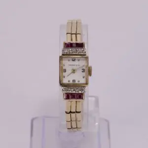Gold wristwatch with red accents.