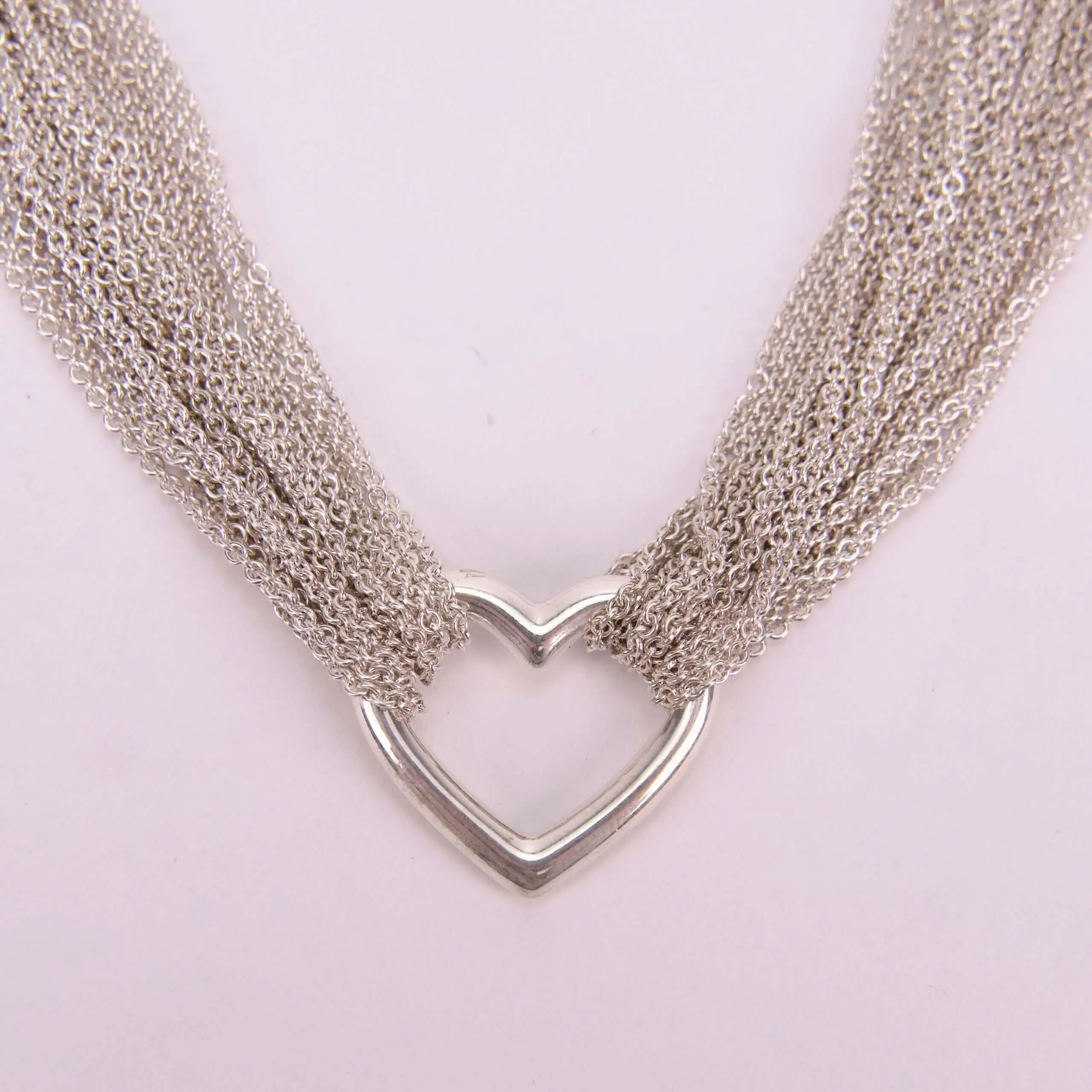 Silver heart necklace with multiple chains.