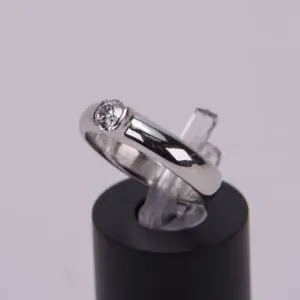 Silver ring with diamond on display stand.