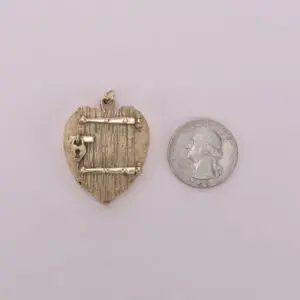 Heart-shaped pendant beside a quarter coin.