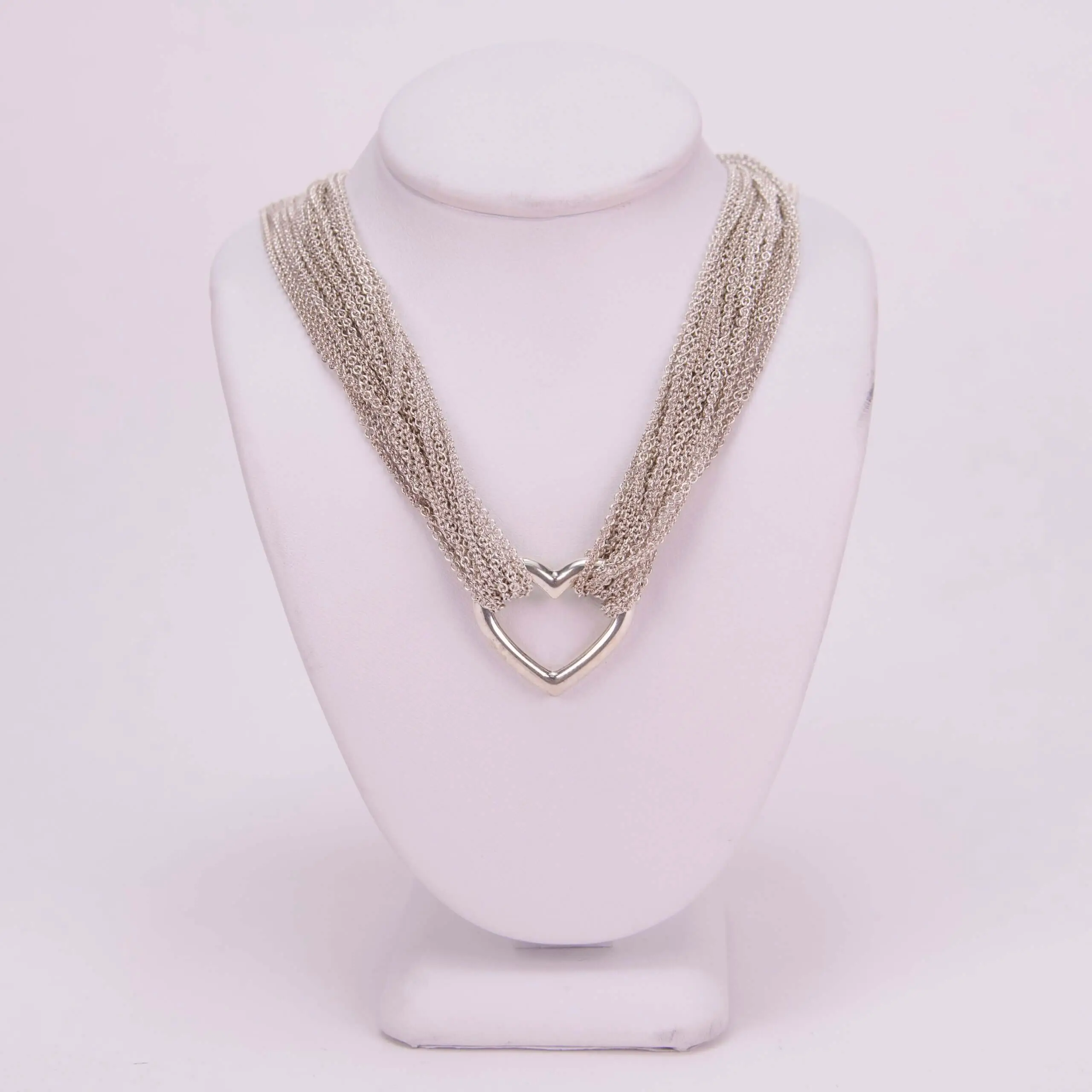 Silver necklace on white display stand.