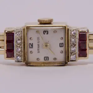 Gold watch with diamonds and red gems.