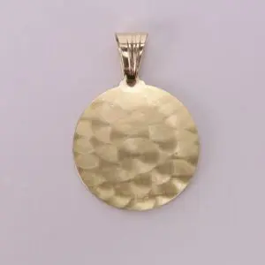 Gold textured round pendant on pink background.