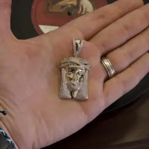 Hand holding a jeweled pendant of Jesus.