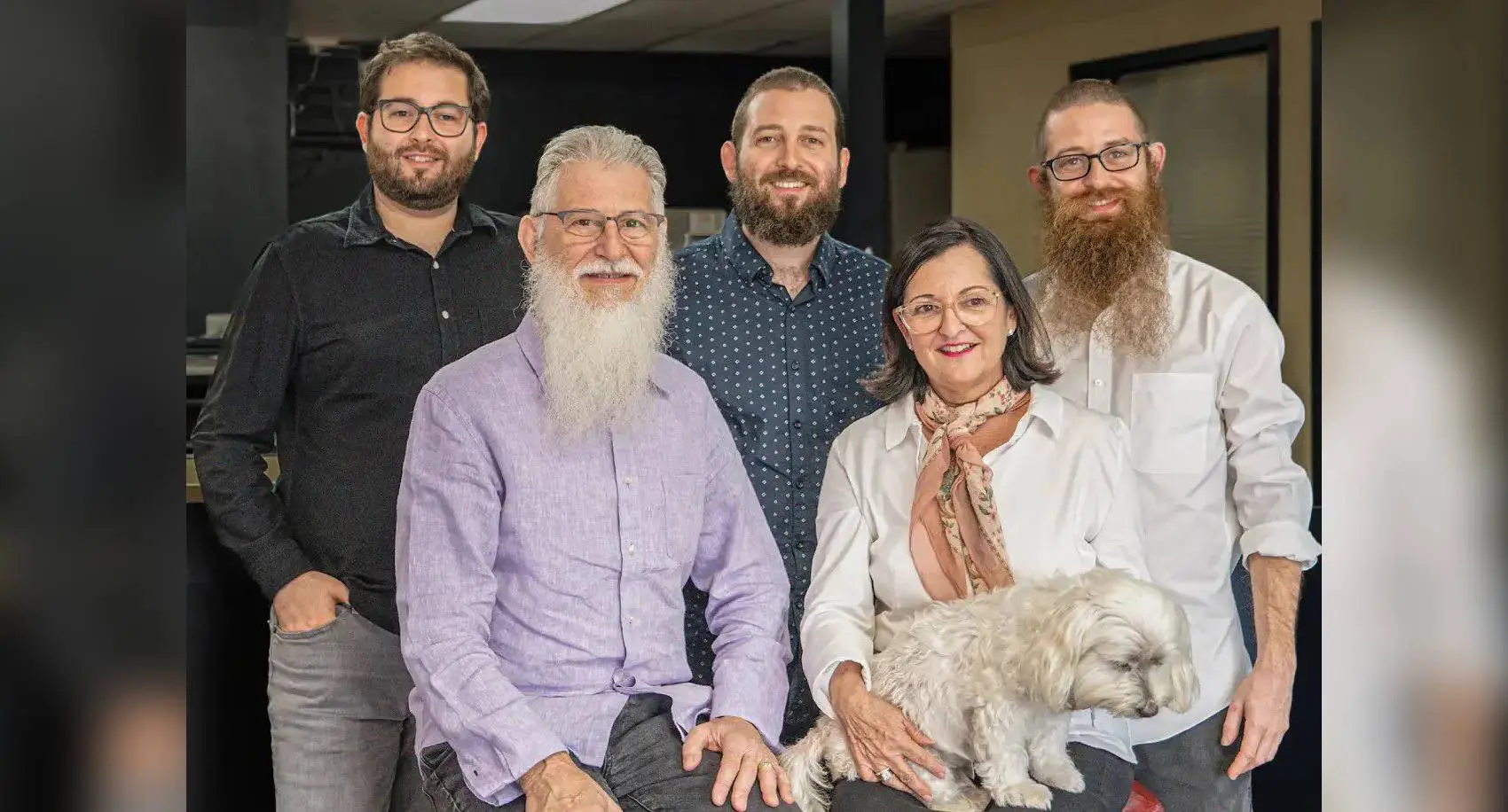 Five people posing with a small dog.