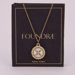 Gold pendant necklace on dark packaging box.
