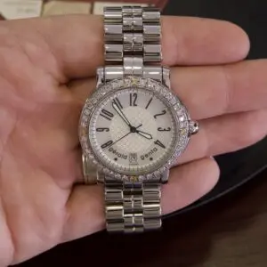 Silver wristwatch with diamond bezel on hand.