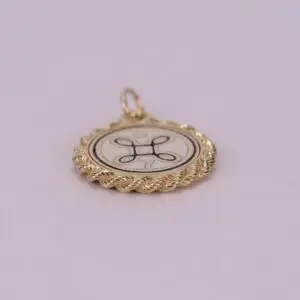 Gold pendant with decorative emblem design.