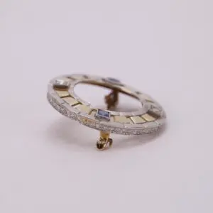 Vintage circular brooch with gemstone accents.