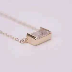 Gold pendant necklace with clear gemstone.