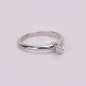 Silver ring with solitaire diamond on display.