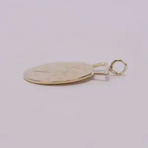 Gold pendant lying on a flat surface.