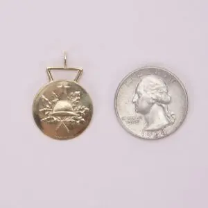 Gold pendant beside a 1964 quarter.