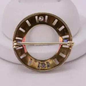 Gold circular brooch with gemstone accents.