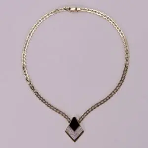 Gold necklace with black and white pendant.