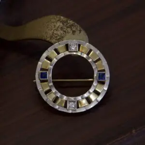 Circular brooch with gold and blue accents.