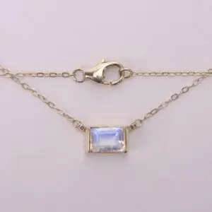 Gold chain with rectangular gemstone pendant.