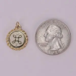 Gold pendant next to a quarter coin.