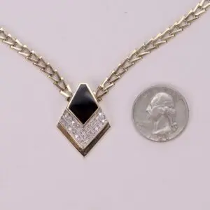 Gold necklace with black pendant and quarter.
