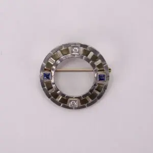 Circular brooch with blue and white stones.