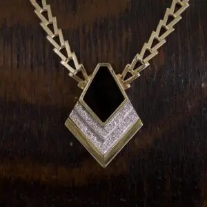Gold necklace with black and silver pendant.