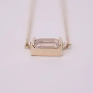 Gold necklace with rectangular gemstone pendant.