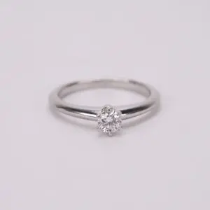 Diamond solitaire ring on white background.