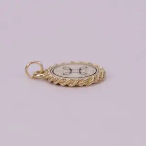 Gold circular pendant with decorative design.