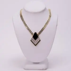 Gold necklace with black and white pendant.
