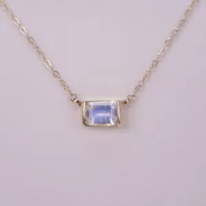 Gold chain necklace with rectangular gemstone.